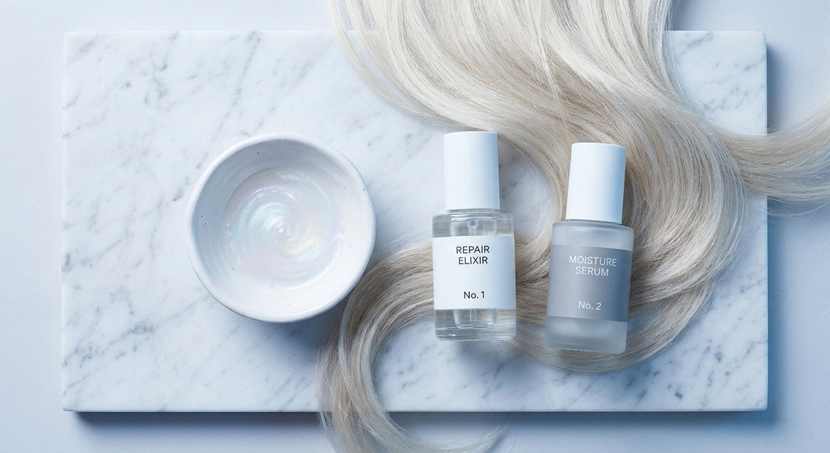 A clean editorial flat lay of premium hair treatment products on white marble, surrounded by silky blonde hair strands and a bowl of pearlescent serum, lit with soft diffused light.